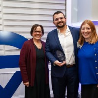 Alex Hogarth poses with two women in front of GVSU logo sign